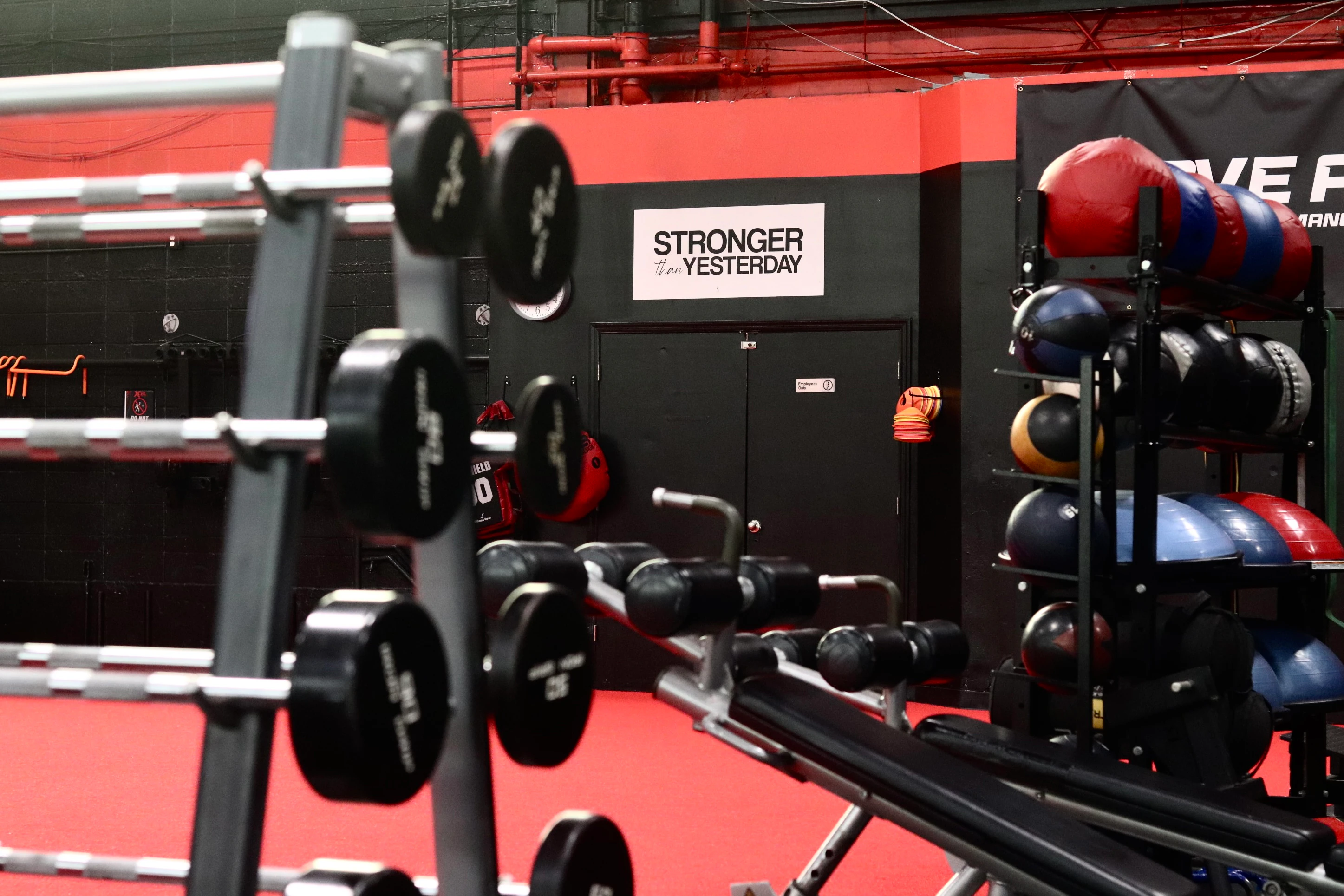 Barbell rack, medicine balls and the Stronger Than Yesterday sign on the turf at XCEL in Fairfield, NJ