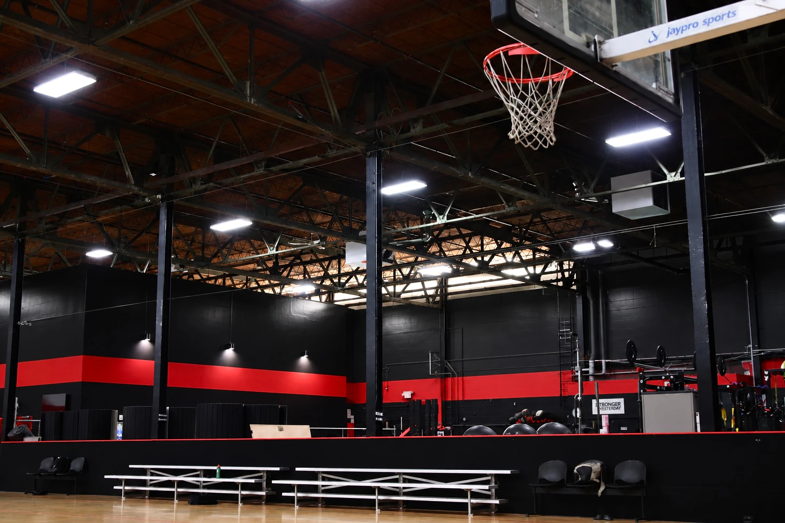 Indoor basketball court with bleachers and a glass backboard at XCEL Sports & Fitness in Fairfield, NJ