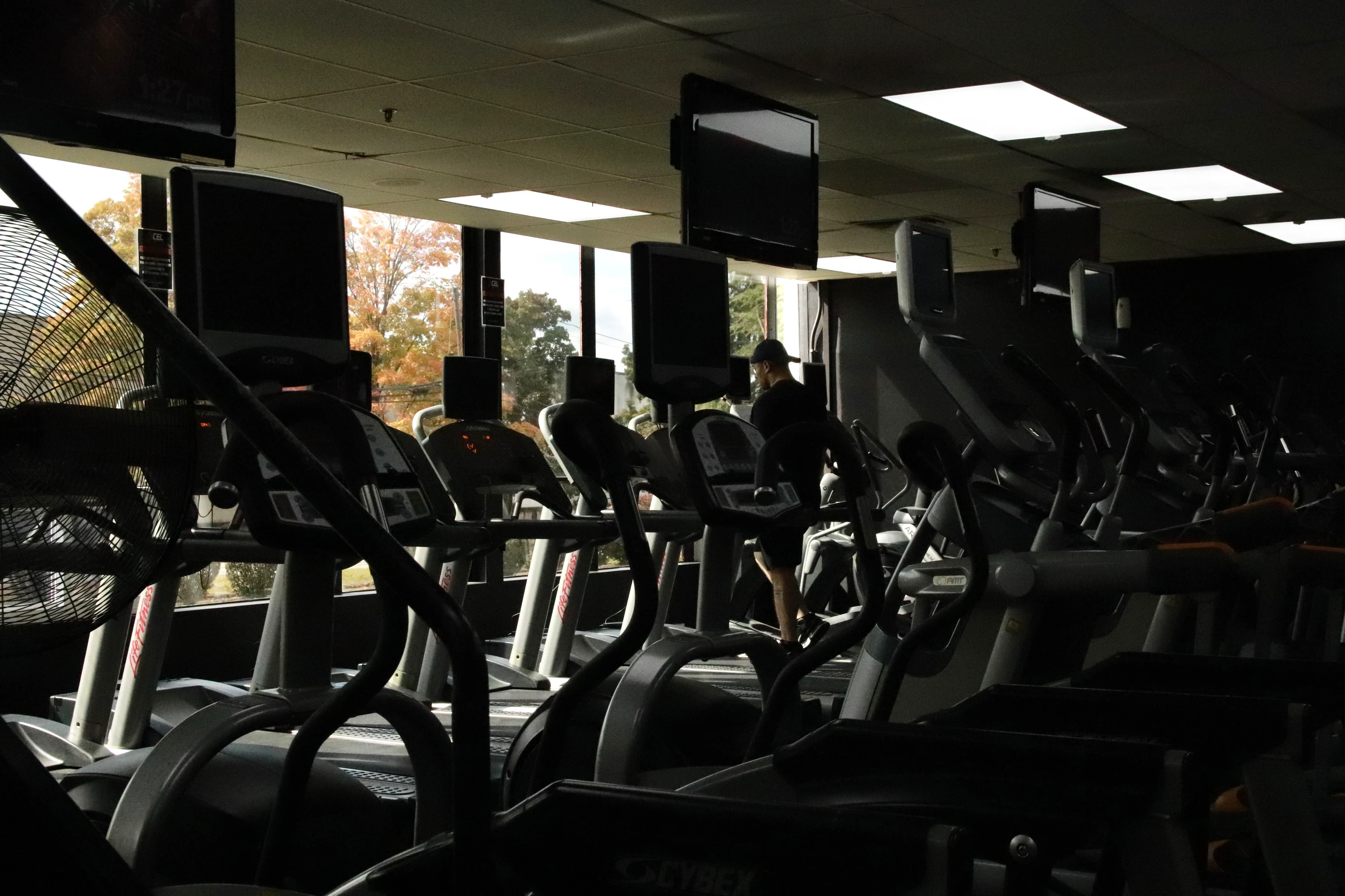 Cardio floor with ellipticals, treadmills and TVs by the windows at XCEL Sports & Fitness in Fairfield, NJ