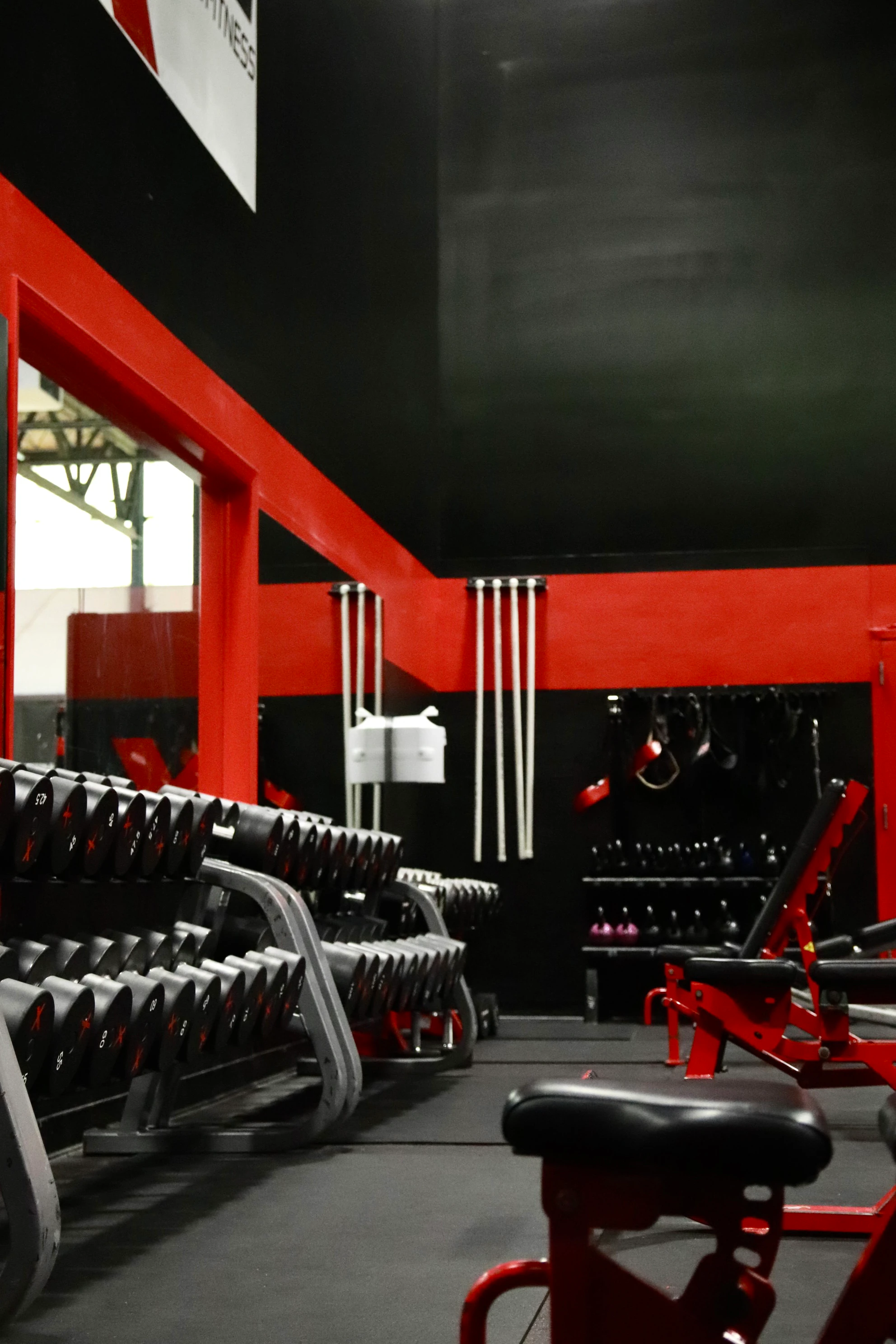 Dumbbell racks along the red wall on the strength floor at XCEL Sports & Fitness in Fairfield, NJ