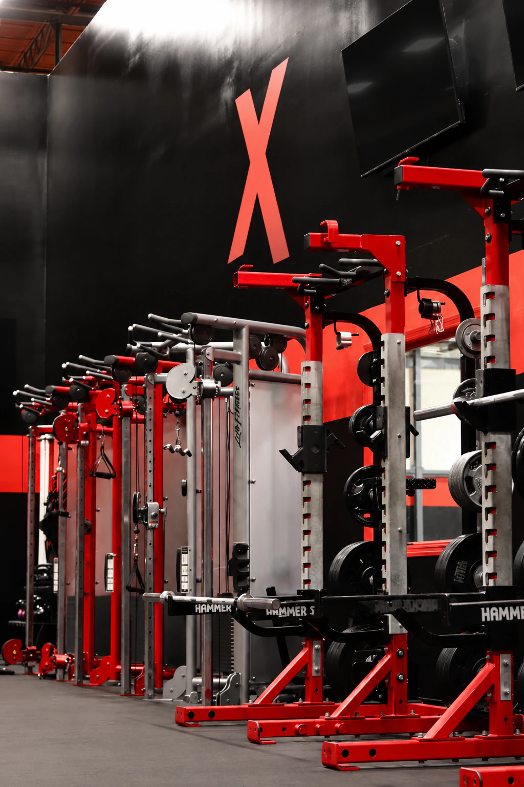 Red Hammer Strength power racks lined up under the red X wall at XCEL Sports & Fitness in Fairfield, NJ