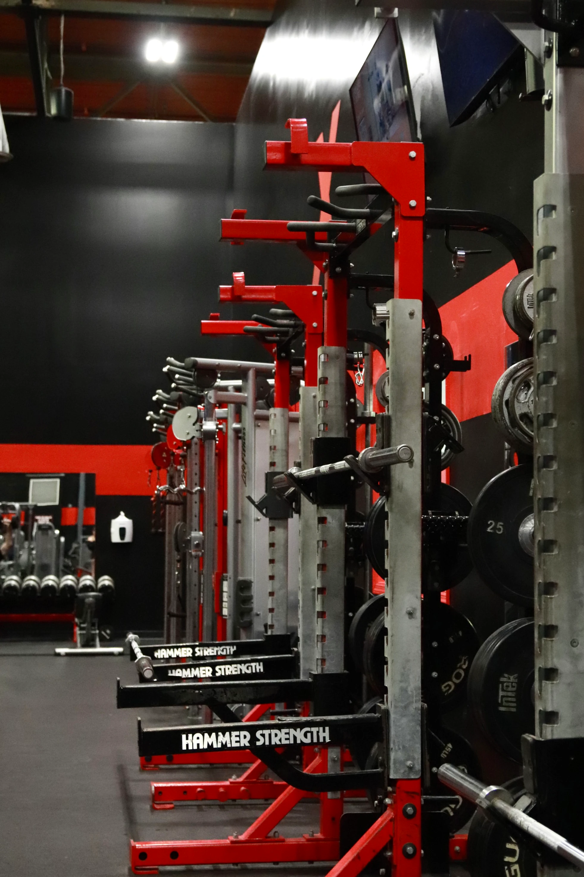 Row of Hammer Strength squat racks with plates at XCEL Sports & Fitness, a gym in Fairfield, NJ