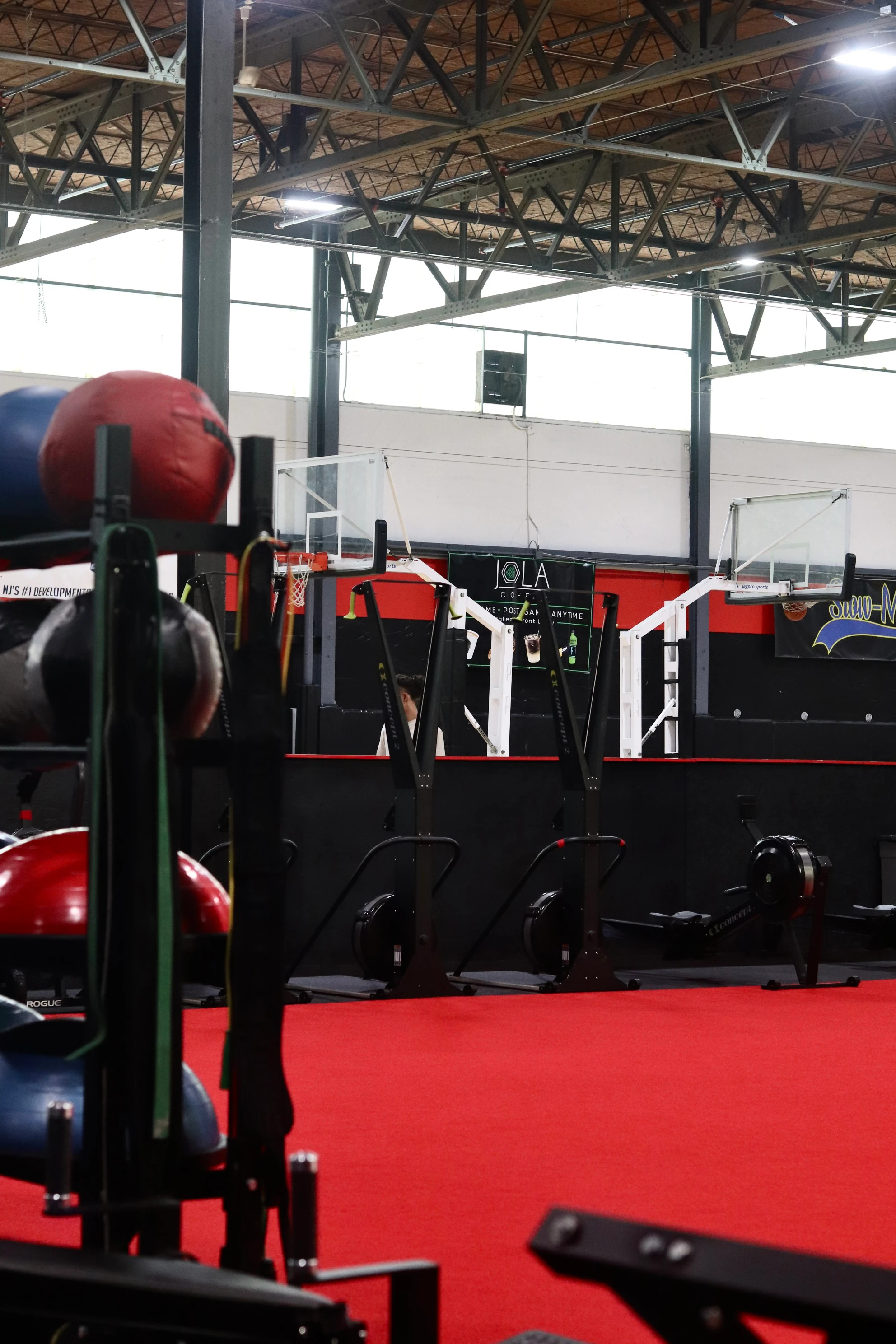 Medicine ball rack on the red indoor turf with the basketball courts beyond at XCEL in Fairfield, NJ