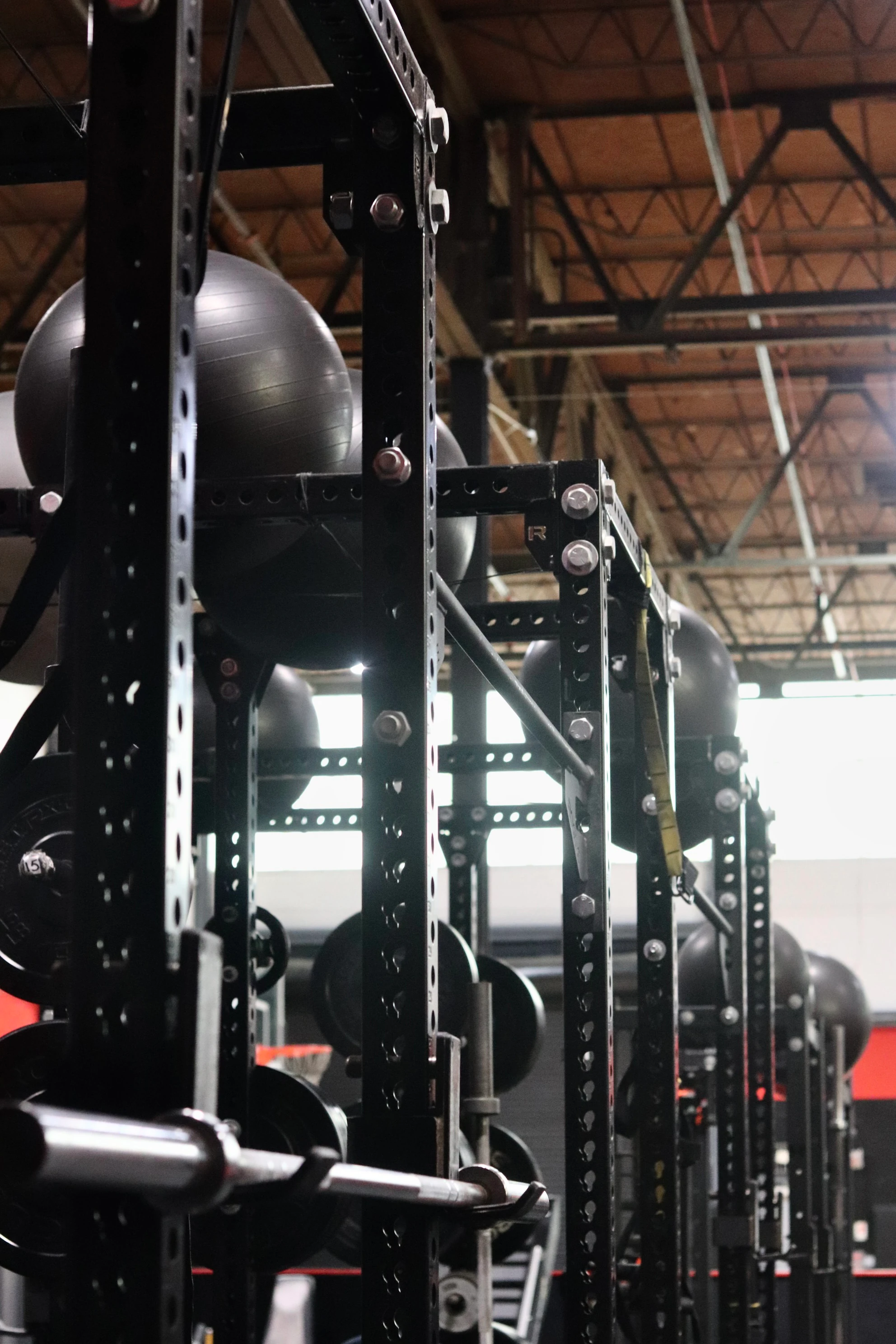 Black squat rig with stability balls stored on top in the performance area at XCEL in Fairfield, NJ