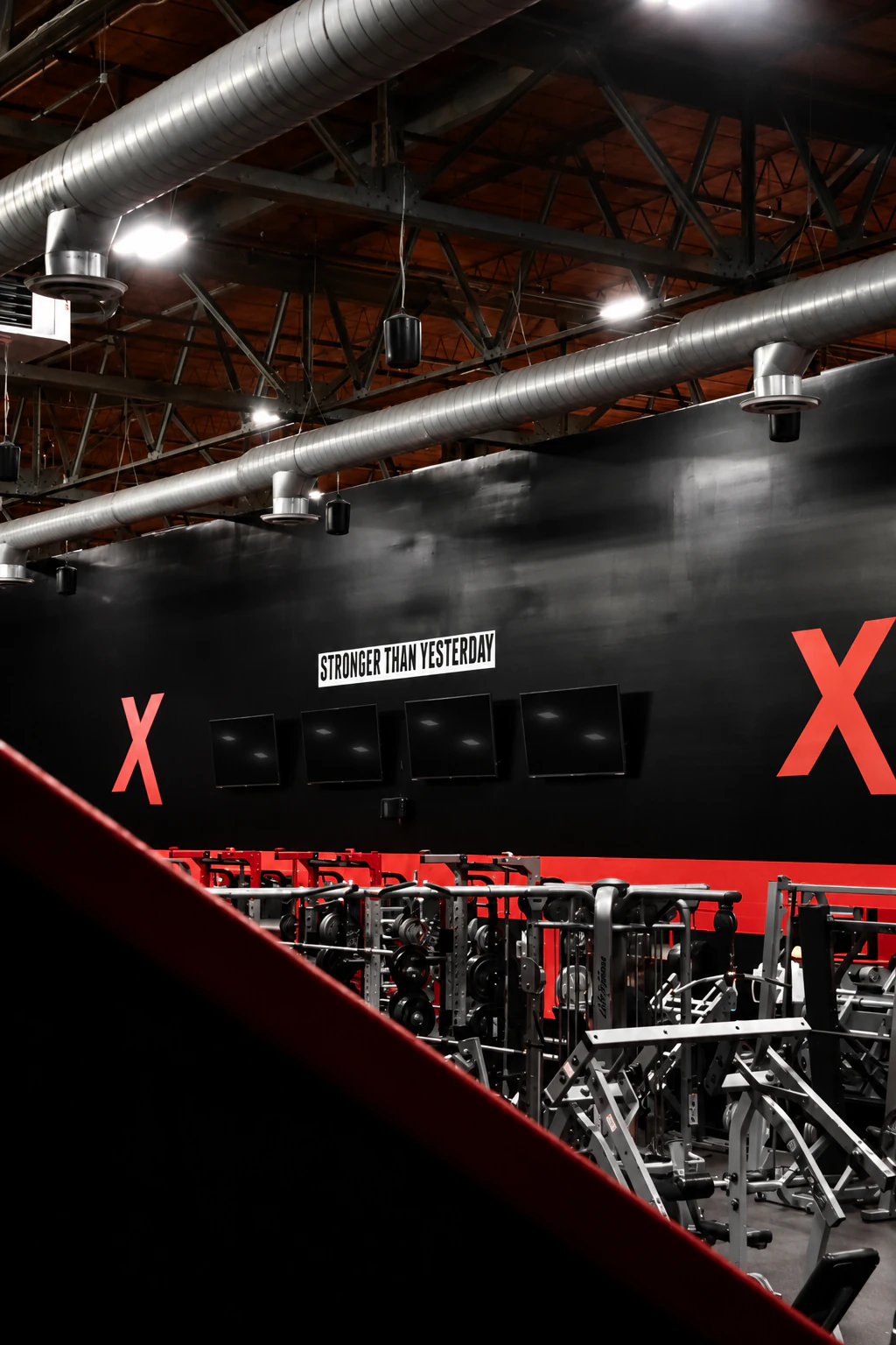 Wide view across the strength floor and its red X wall at XCEL Sports & Fitness, a gym in Fairfield, NJ