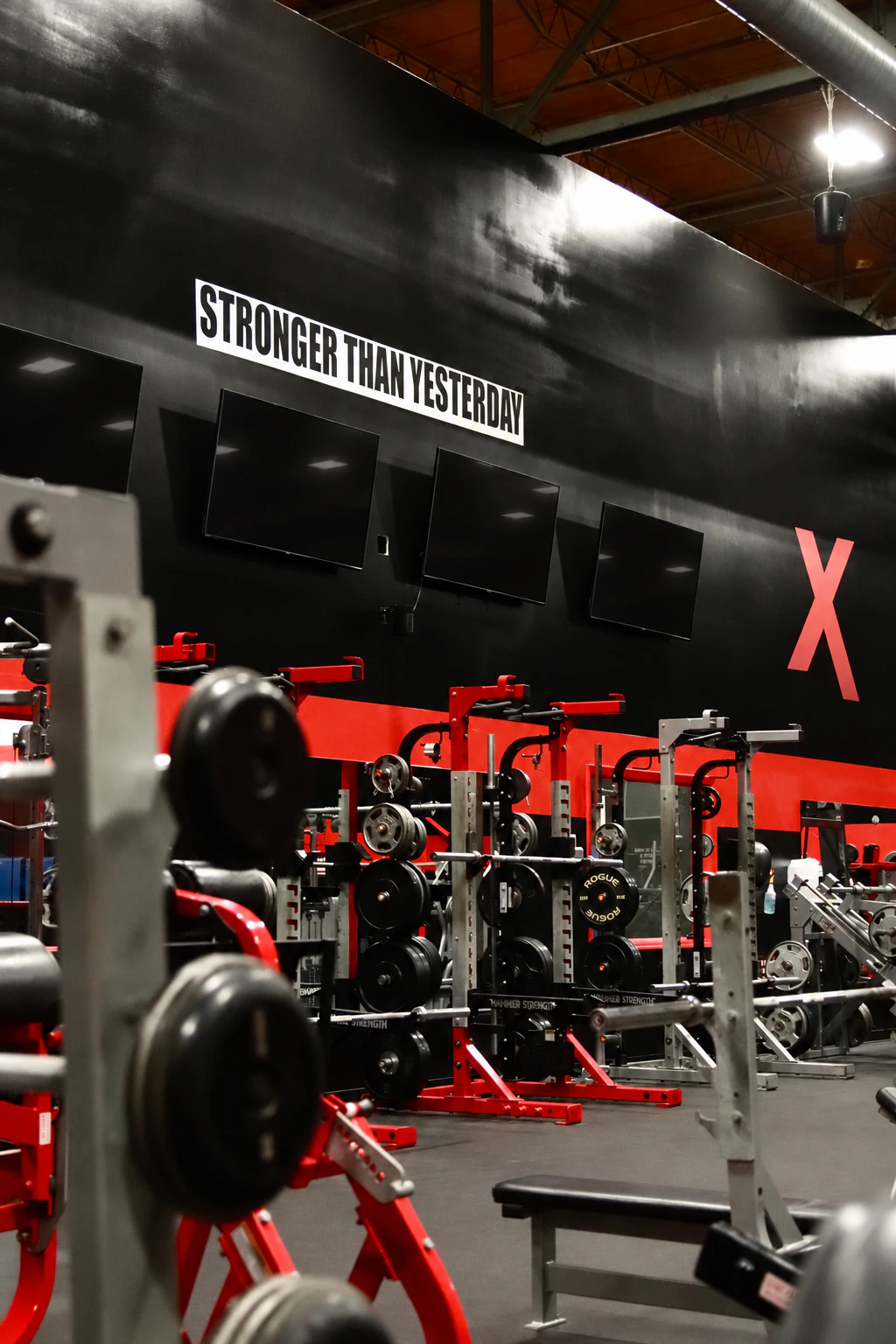 Stronger Than Yesterday wall above plate-loaded machines on the strength floor at XCEL in Fairfield, NJ