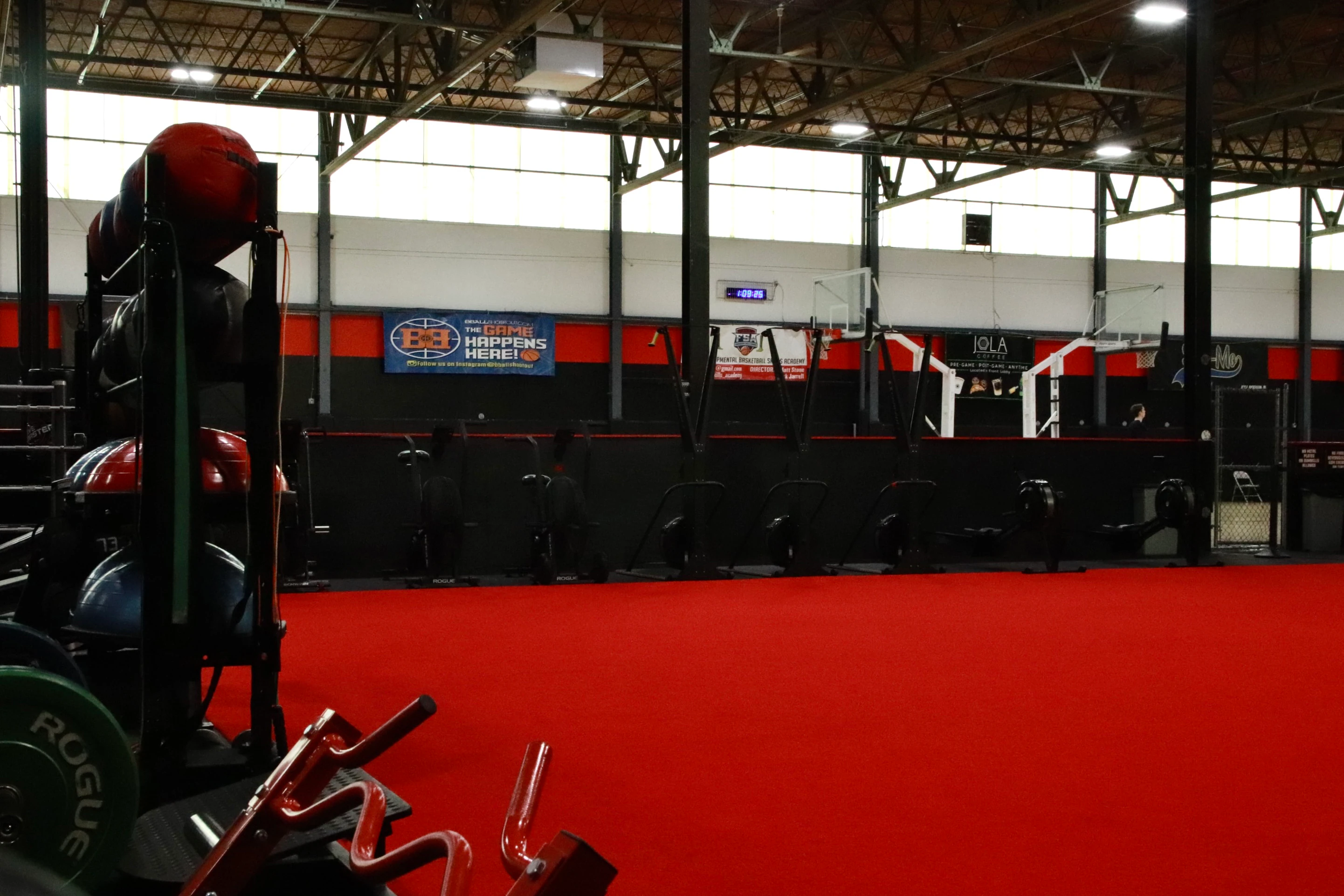 Red indoor turf with a medicine ball rack and the basketball courts beyond at XCEL in Fairfield, NJ