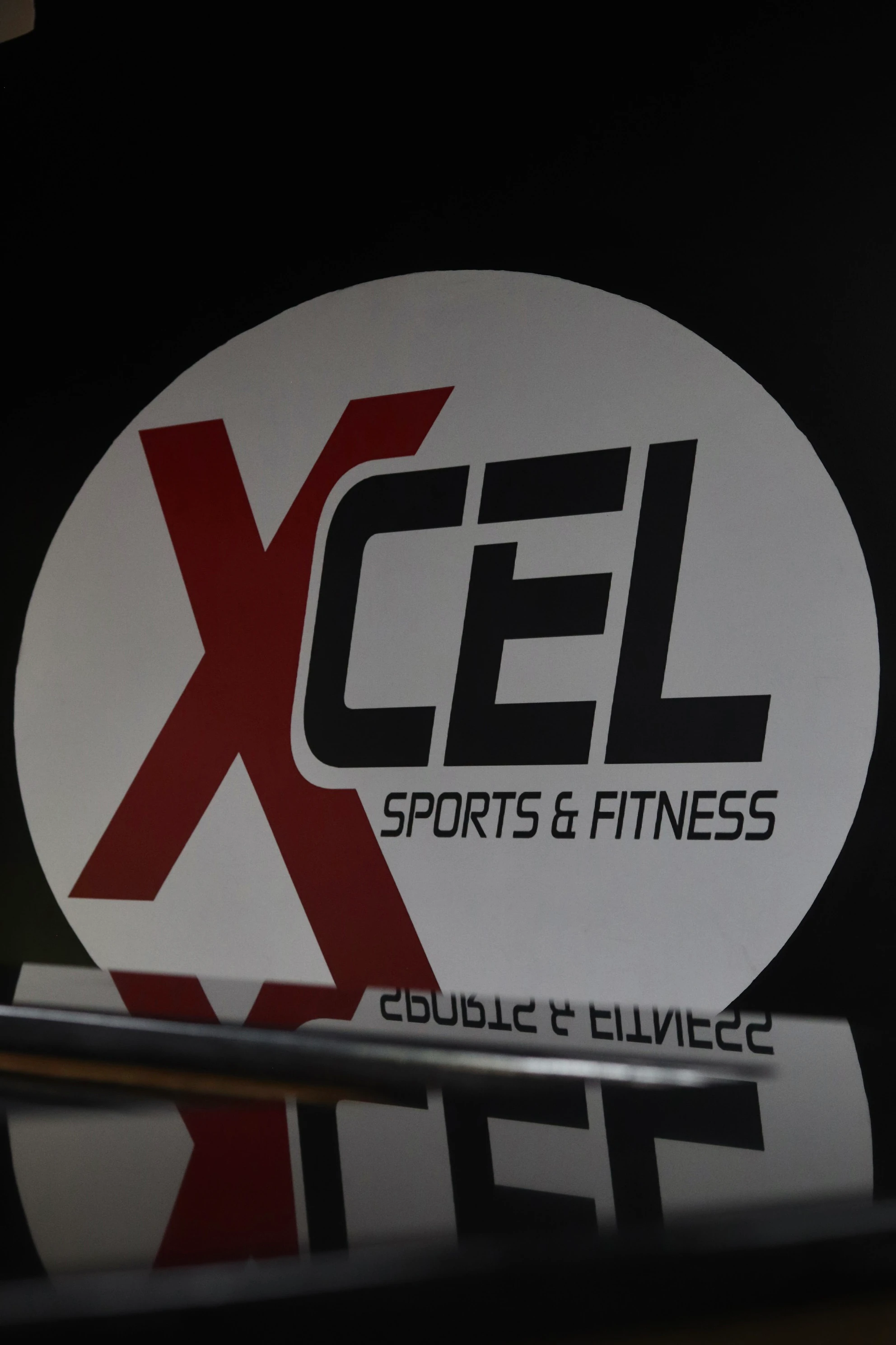 XCEL Sports & Fitness logo reflected in a mirror at the gym in Fairfield, NJ