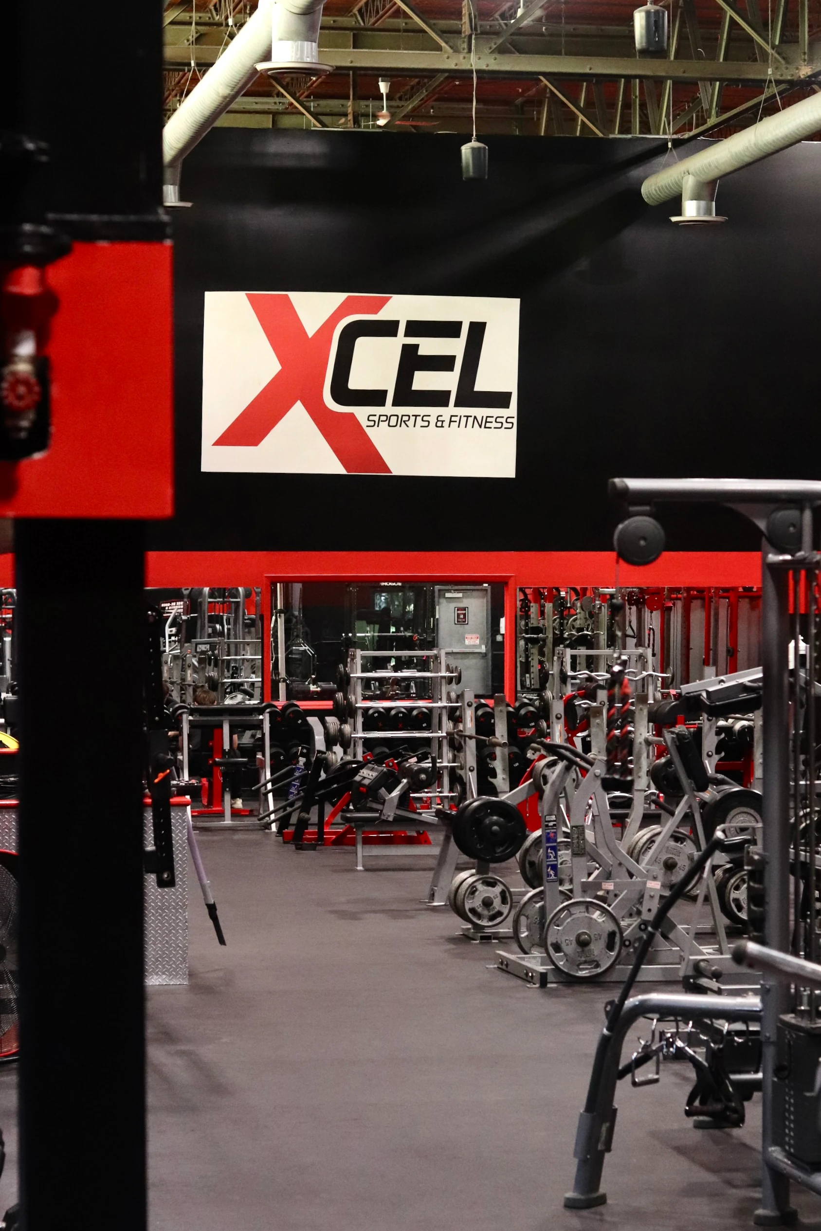 XCEL sign over cable machines and racks on the strength floor at XCEL Sports & Fitness, Fairfield, NJ