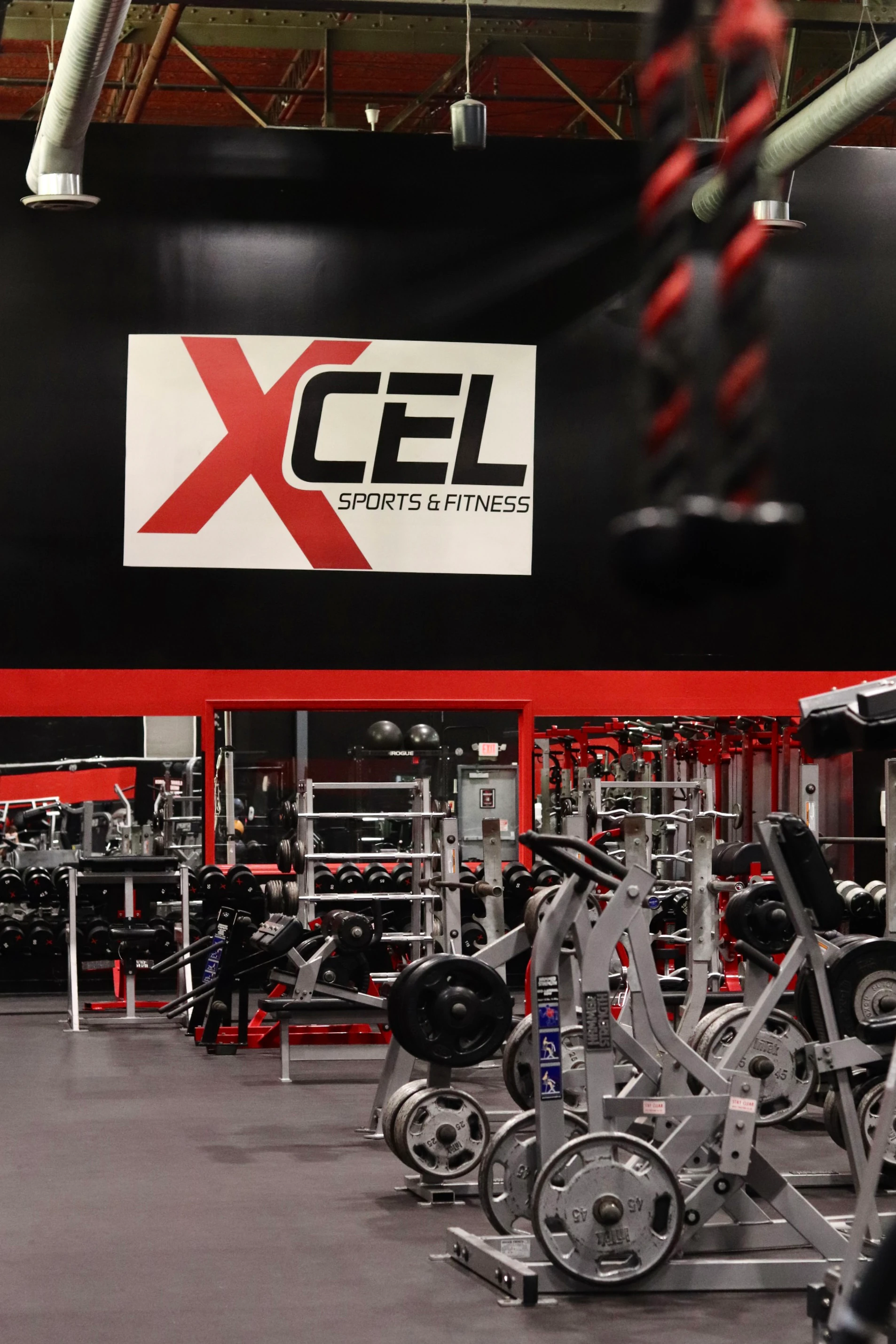XCEL sign above plate-loaded machines with a battle rope in front at XCEL in Fairfield, NJ